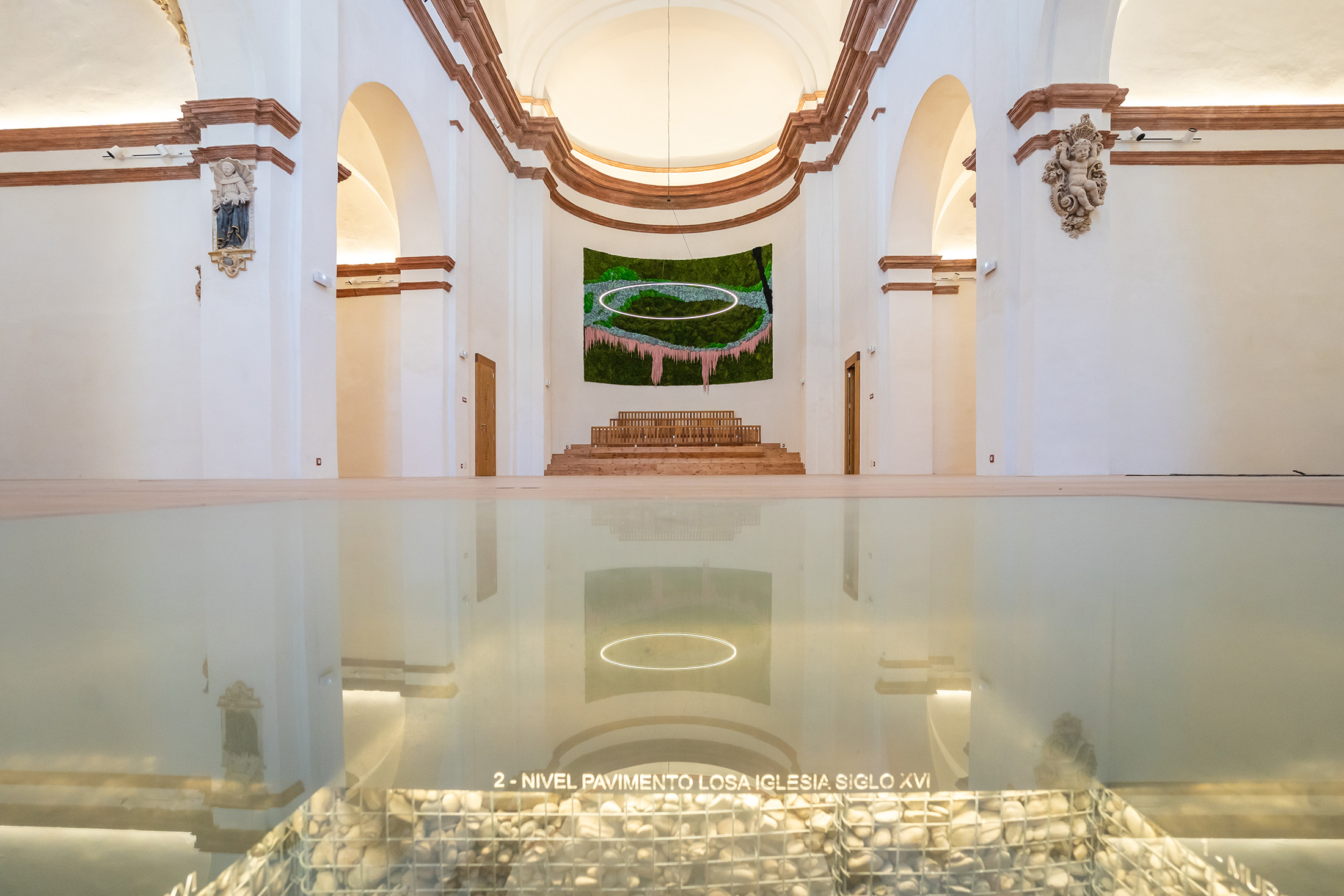 Interior rehabilitado de la iglesia de San Nicolás con suelo de madera e instalación visual en el ábside
